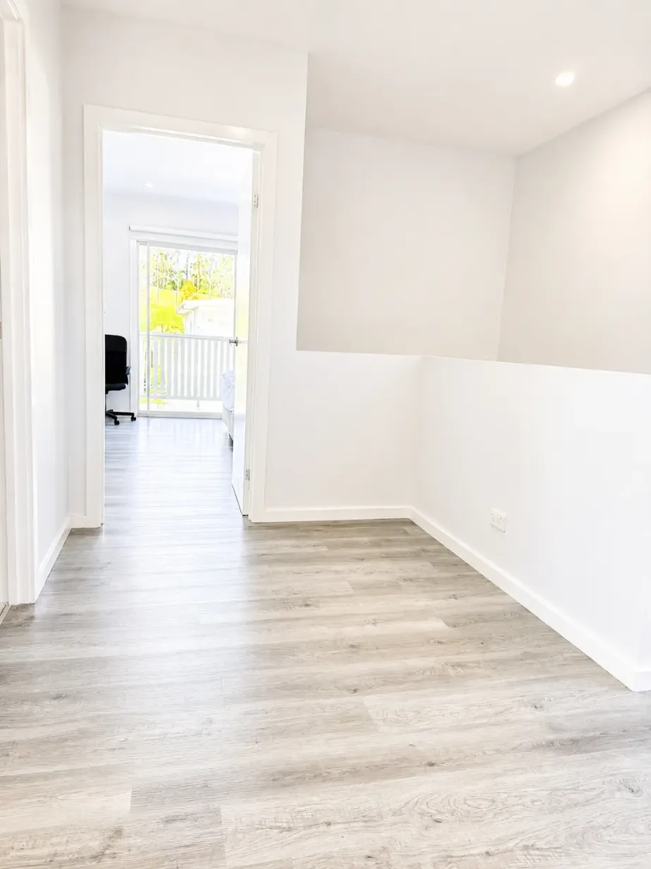 Upstairs landing with timber-look flooring leading to a bedroom with balcony access